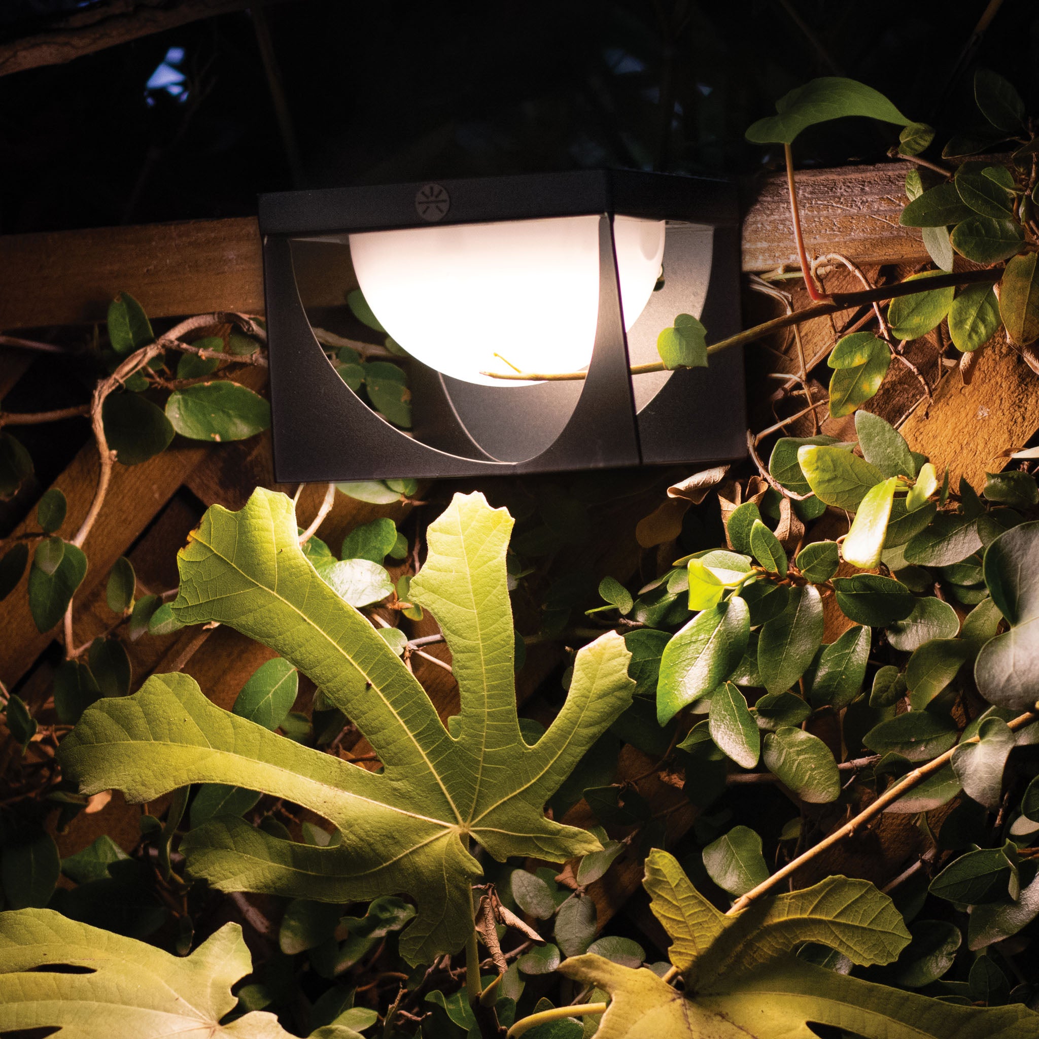 Les Jardins Flow sconce lighting up fence garden